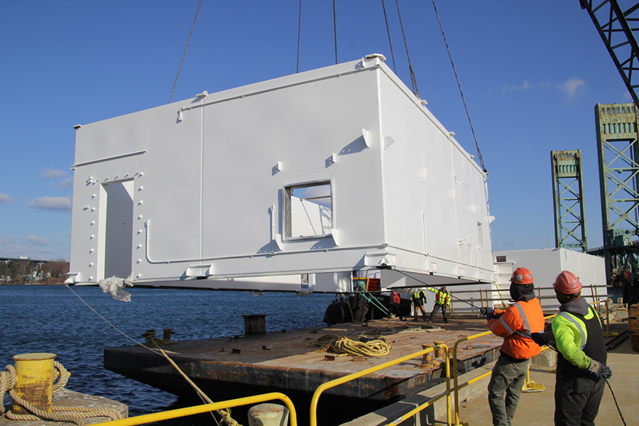 Loading a piece of the modular unit onto a barge for transport